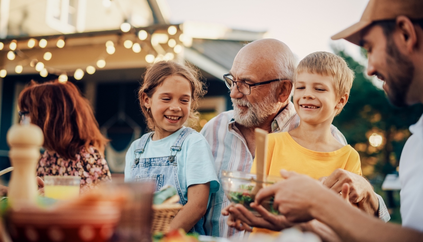 A grandpa sits with two of his grandkids at a family dinner.