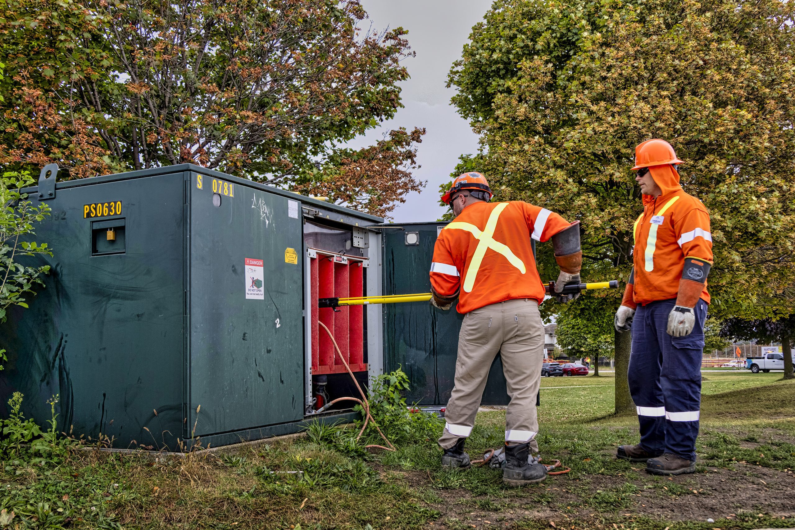 Two energy workers service a transformer.