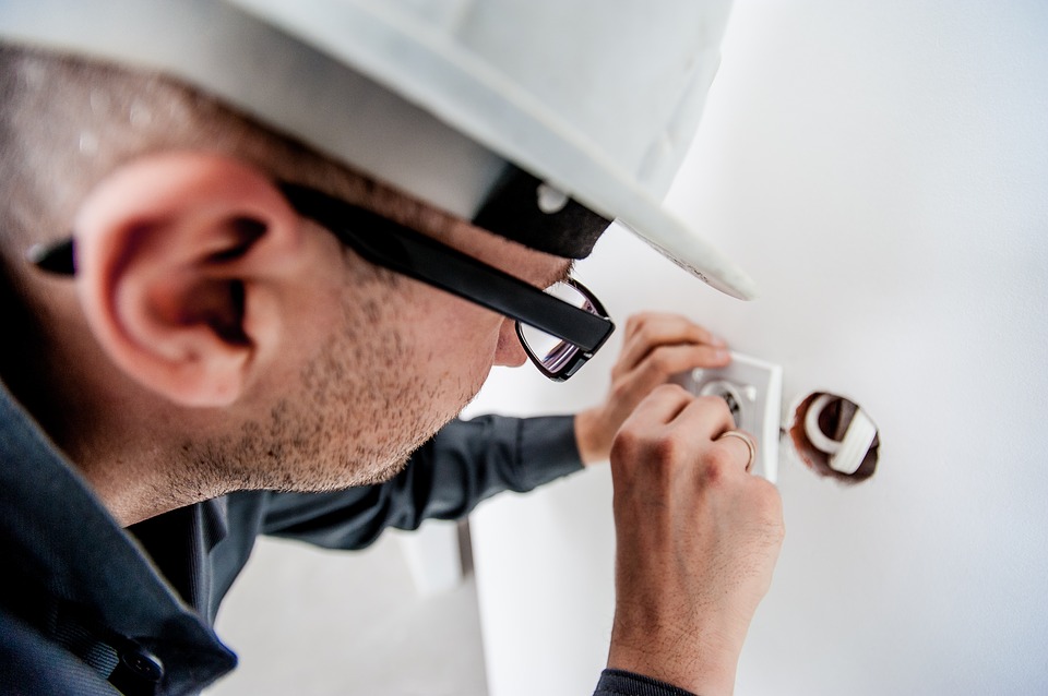 An electrician focuses intently as they work on an electrical outlet.