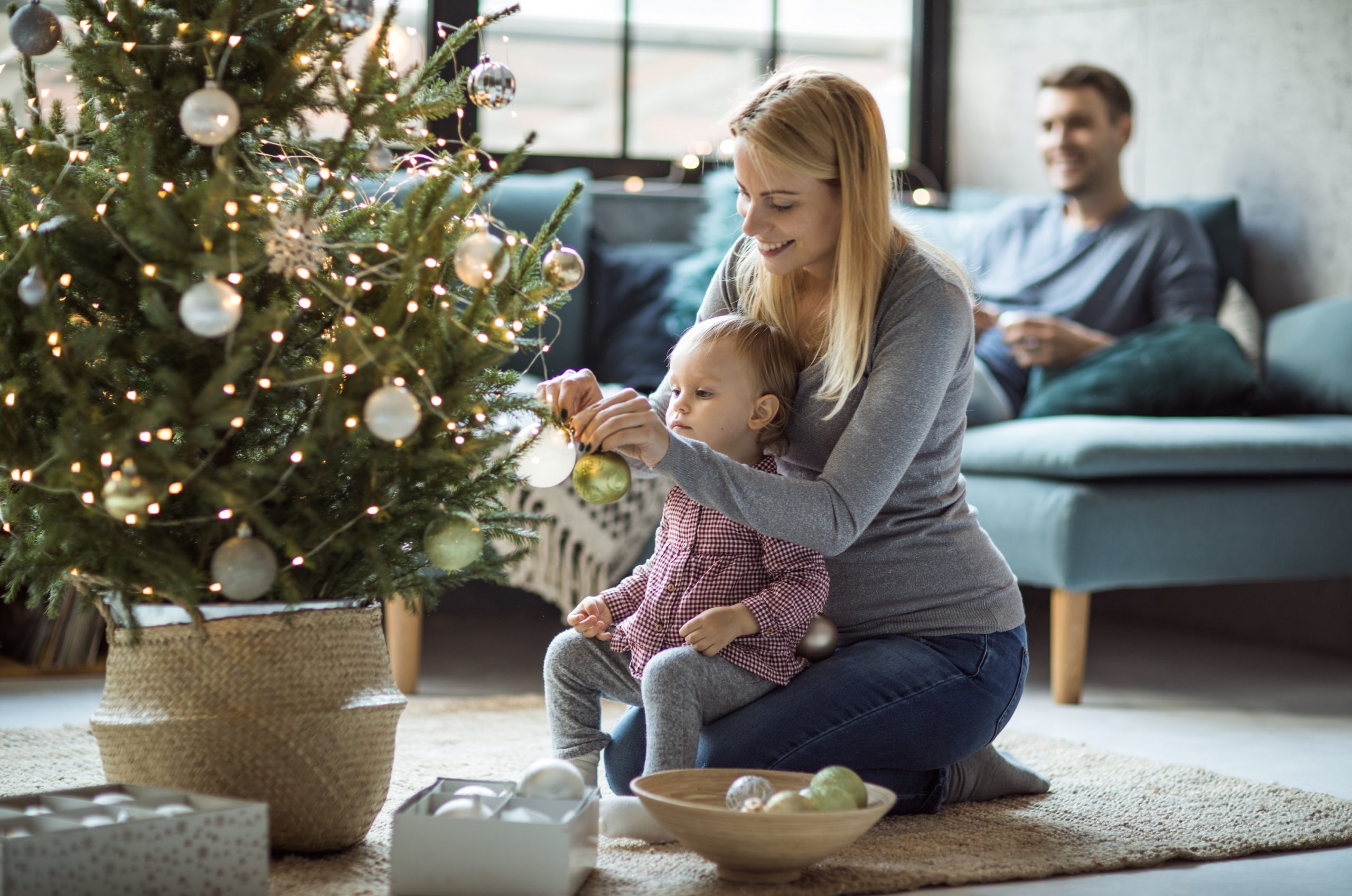 A mother and her small child hanging ornaments on a Christmas tree.