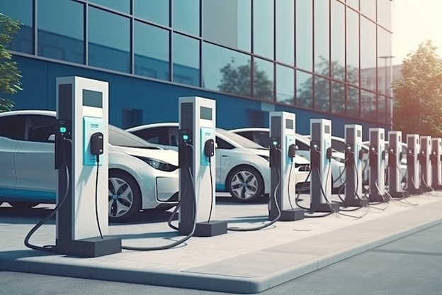 A row of electric vehicles at outdoor charging stations.