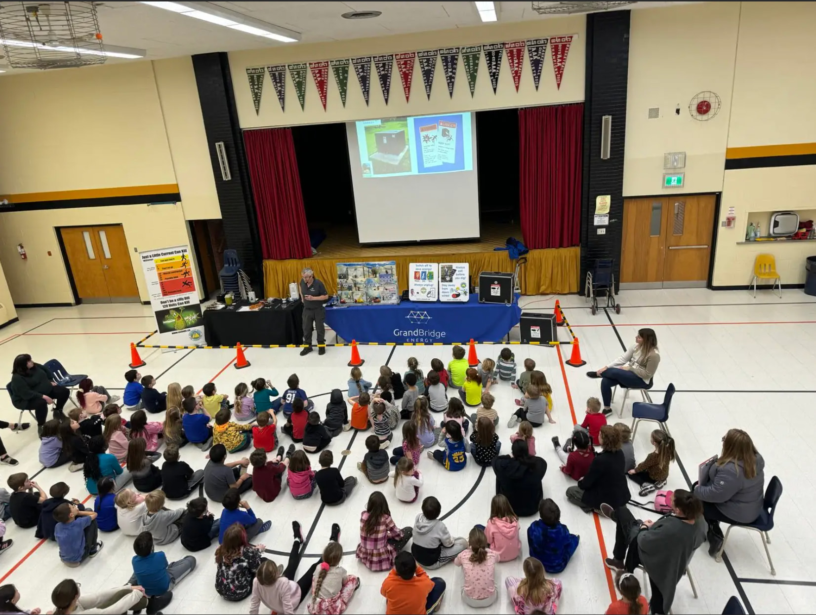 A group of students sit in front of a projector screen while learning about electrical safety