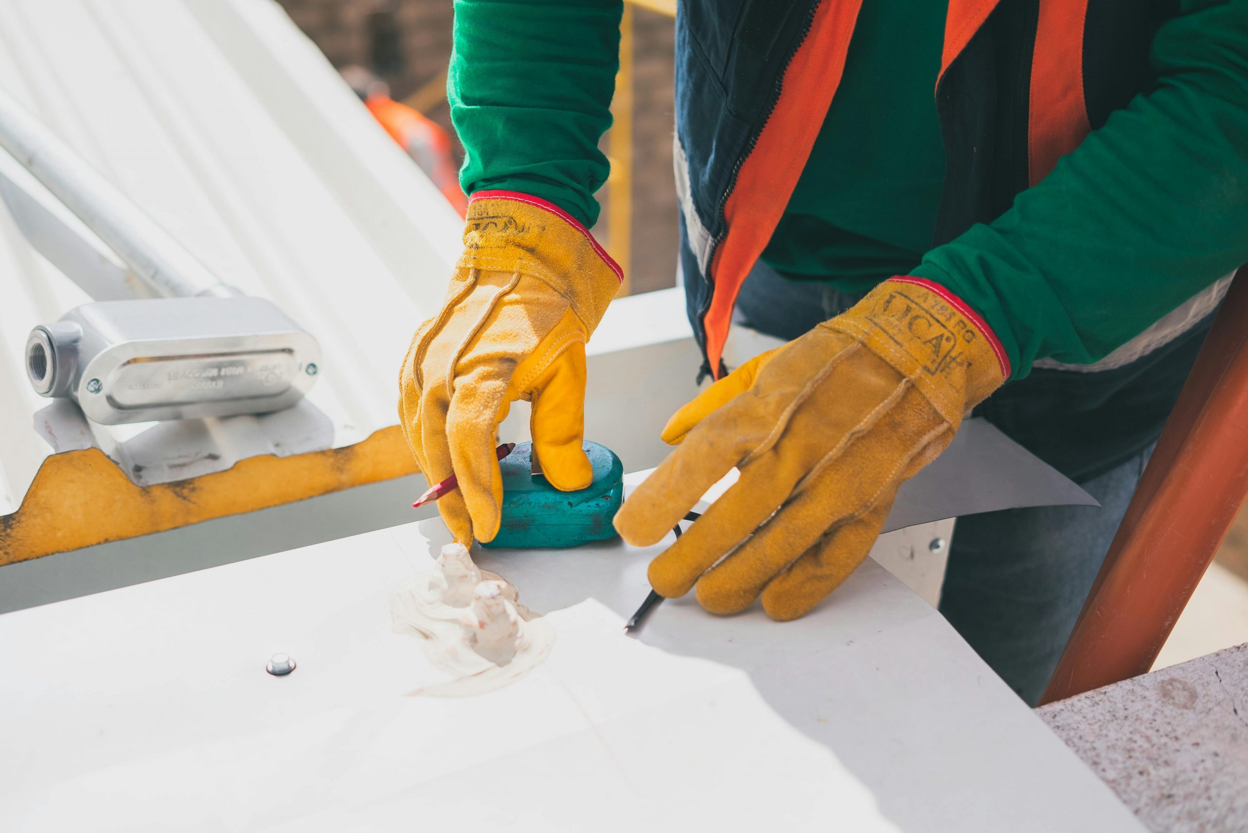 A construction worker with gloves on taking measurements of a material.