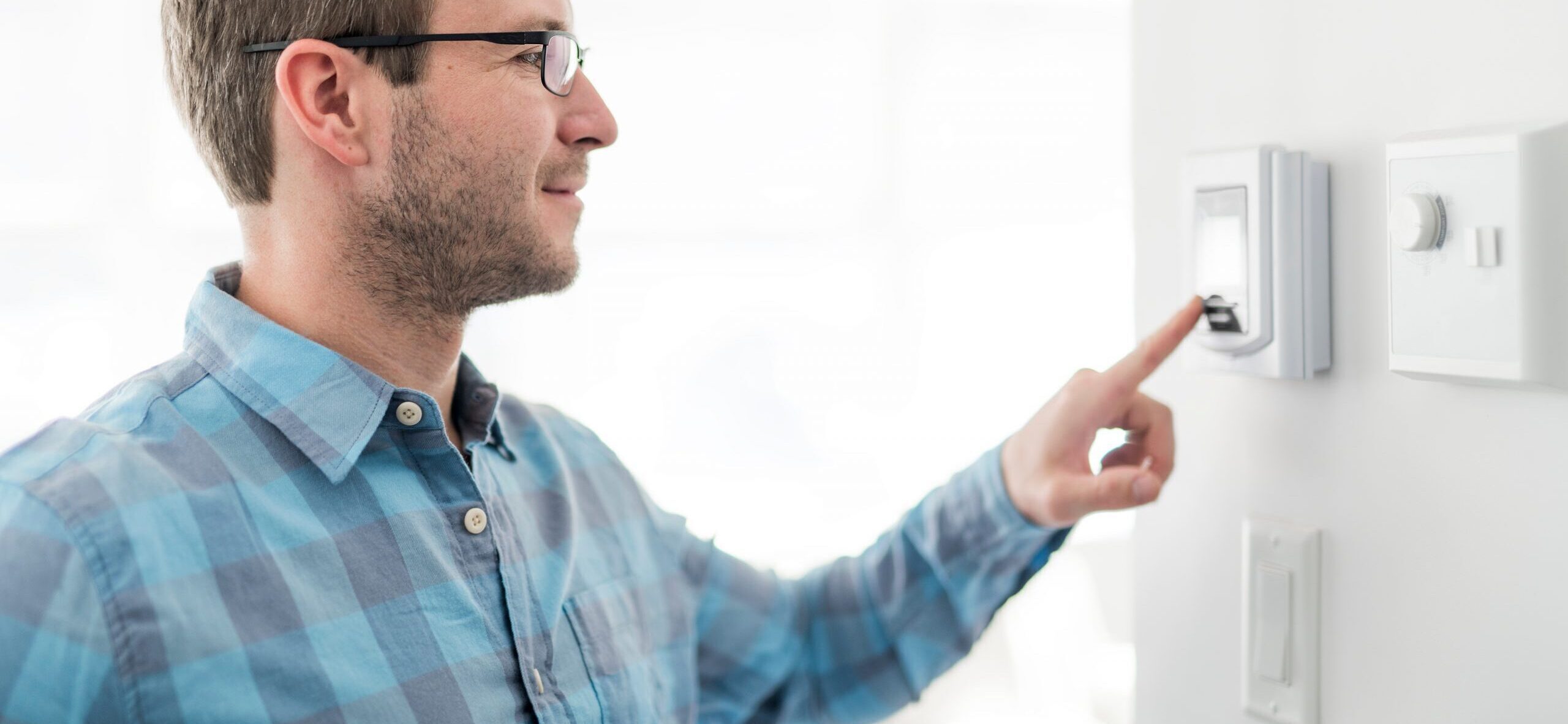 A man adjusts his thermostat to improve efficiency.