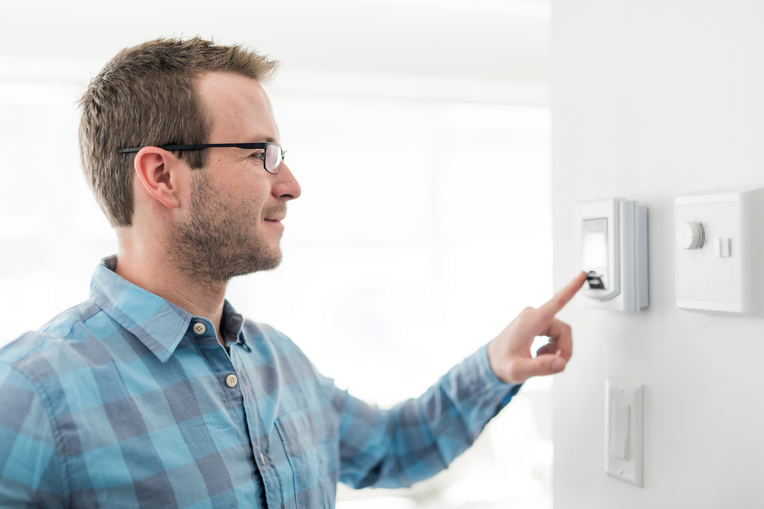 A man adjusts his thermostat to improve efficiency.