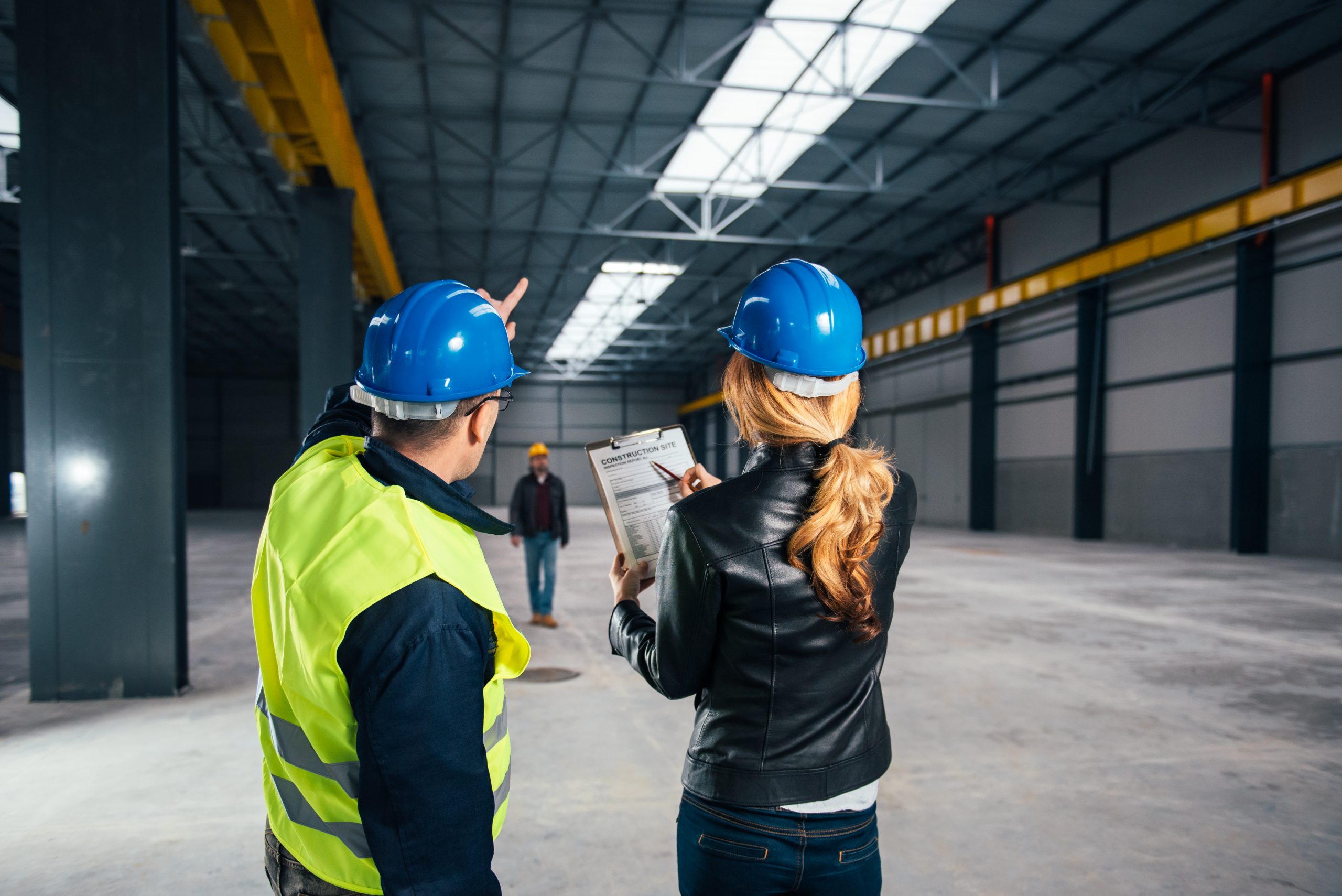 Contractors reviewing plans in an empty warehouse