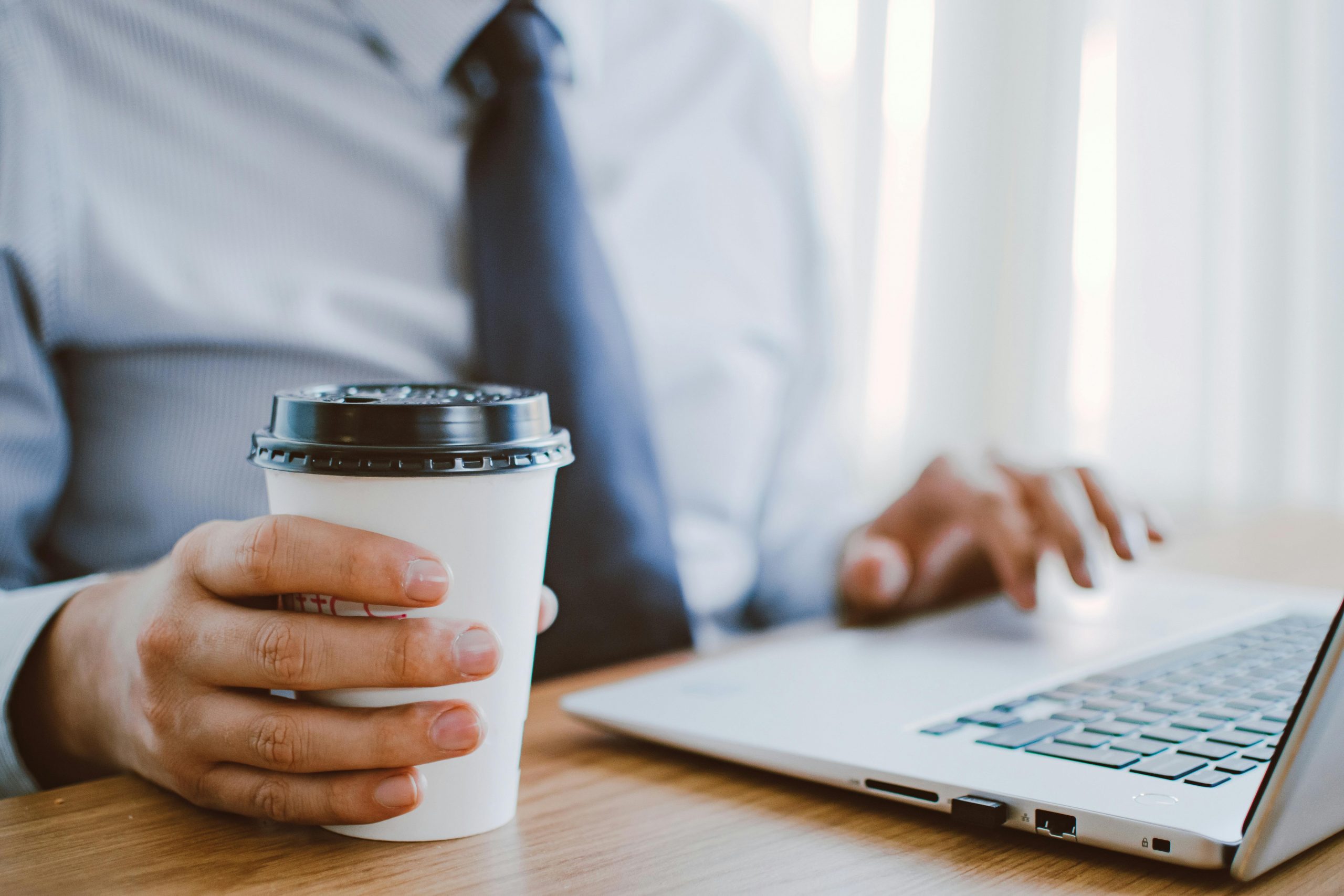 Hands typing on a computer while holding a coffee mug