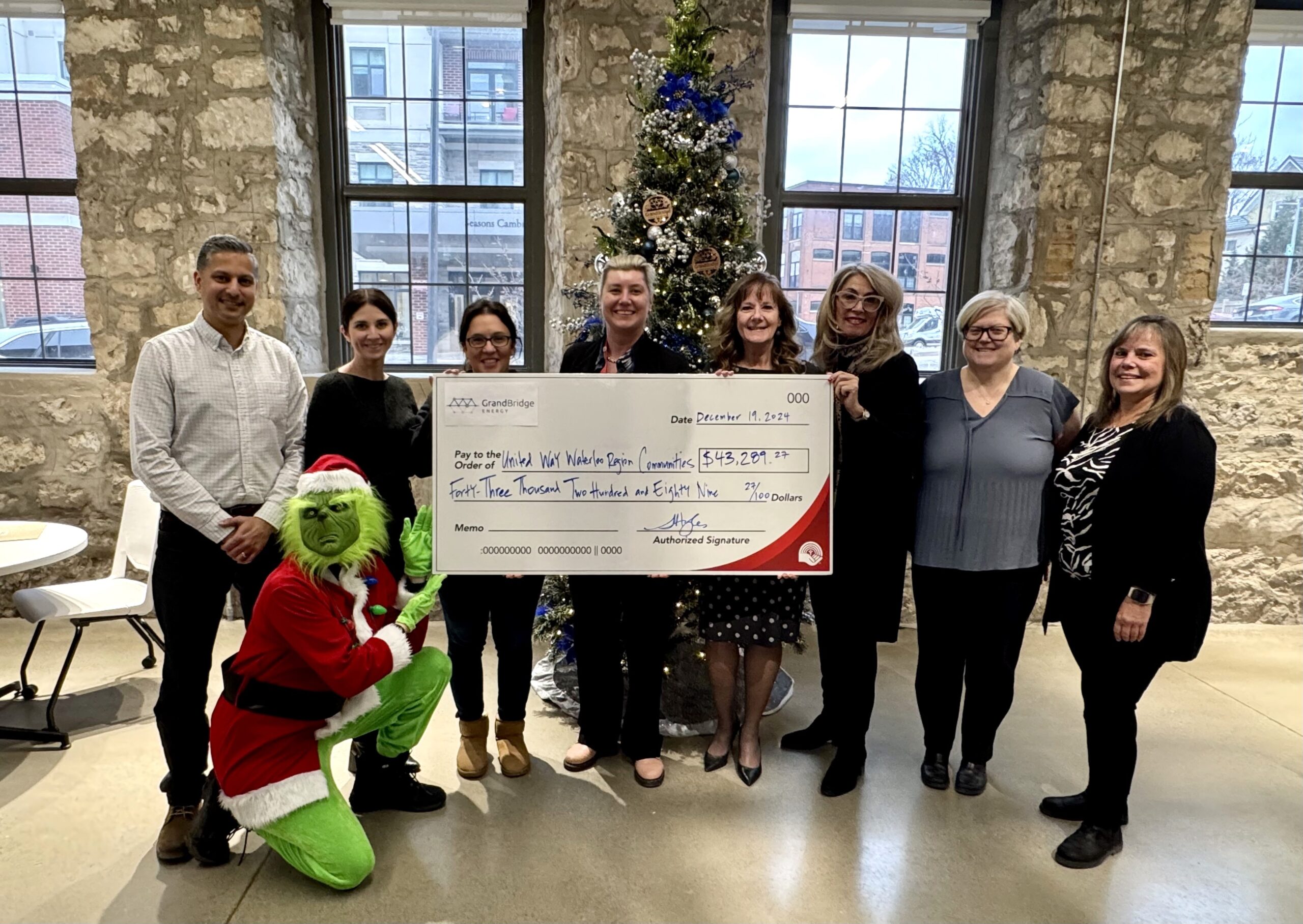 employees and the grinch presenting a cheque for $43,289 to the United Way representatives