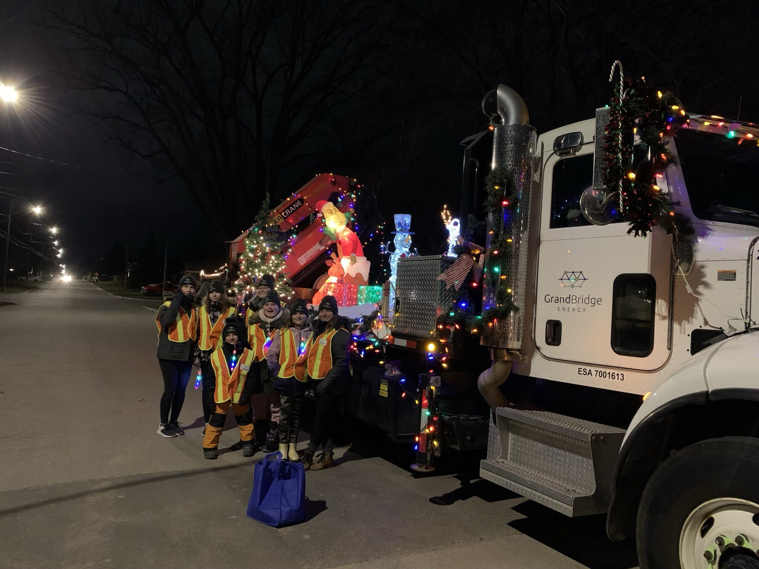 a group of people gather outside a large parade float at night.