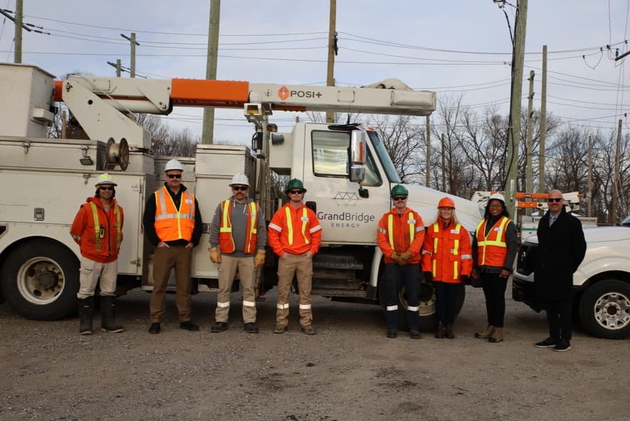 Group of people standing in front of utlity truck.