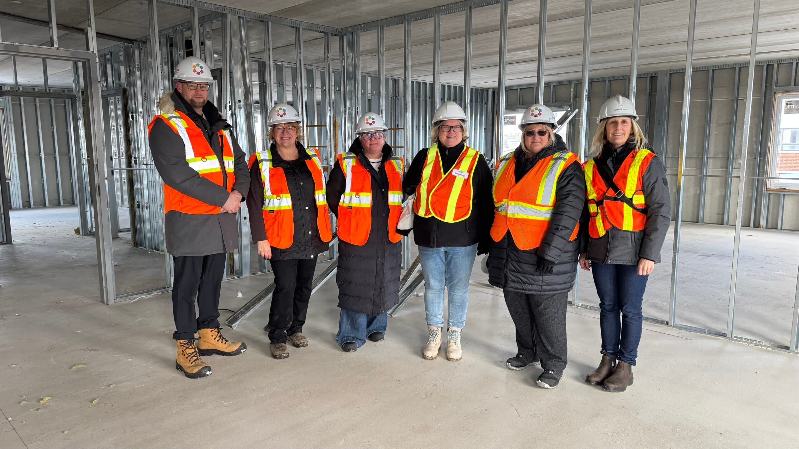 GrandBridge employees along with officials from Jaycees Non Profit Housing pose in an under construction housing project for women-led families.