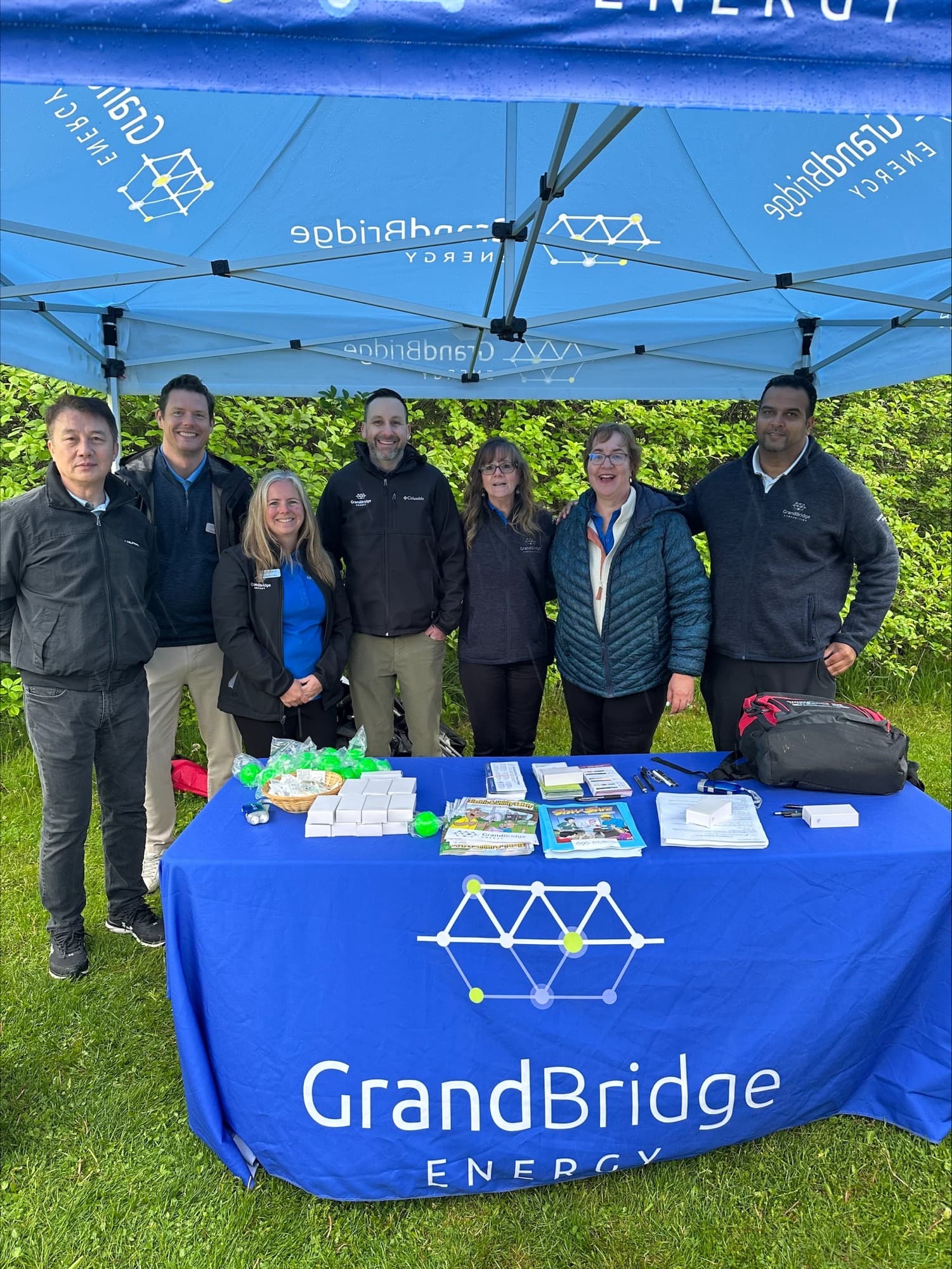 Seven employees standing at the GrandBridge Energy booth at the Six Nations Fair.