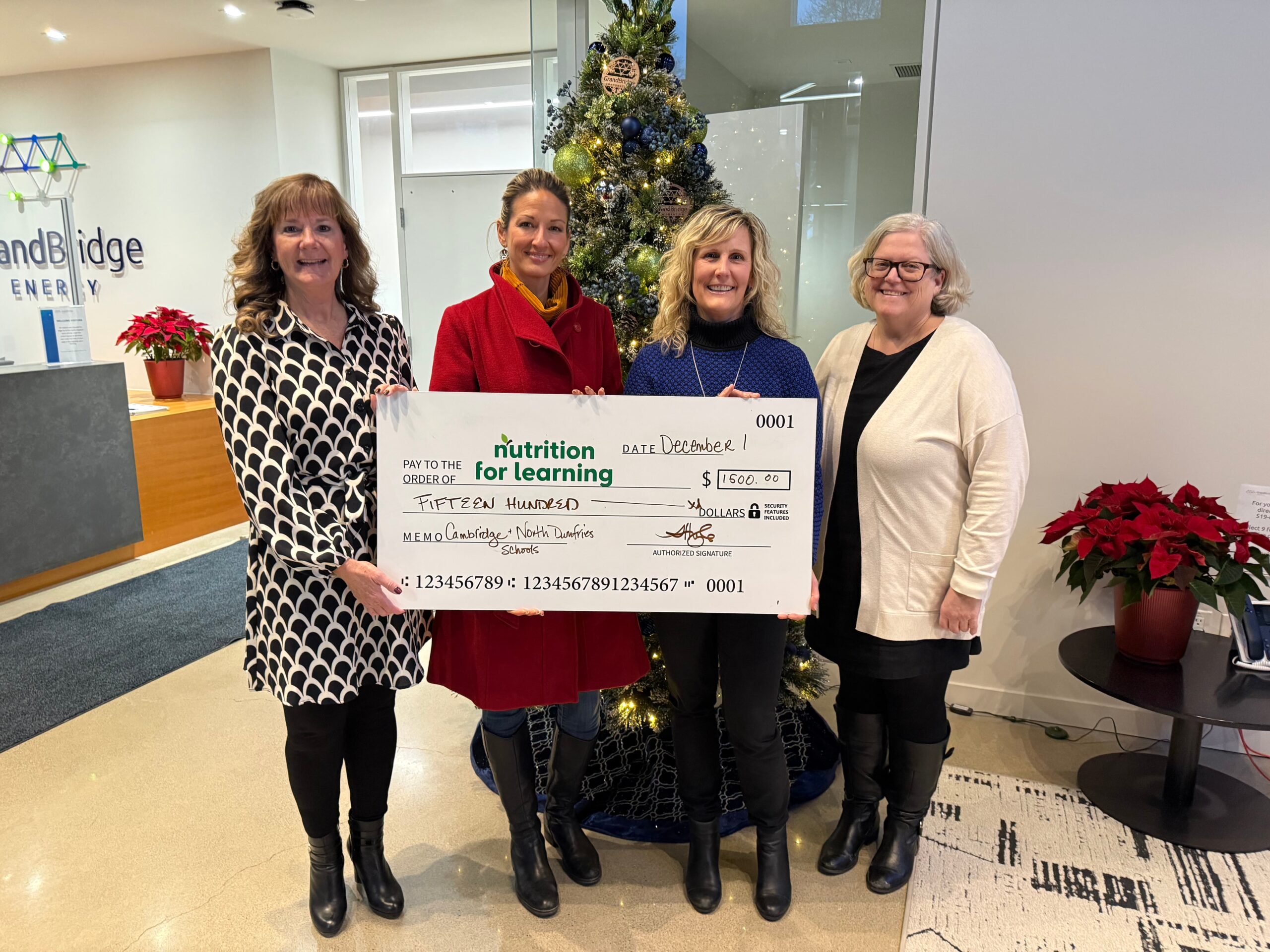 Employees hold large cheque for Nutrition for Learning.