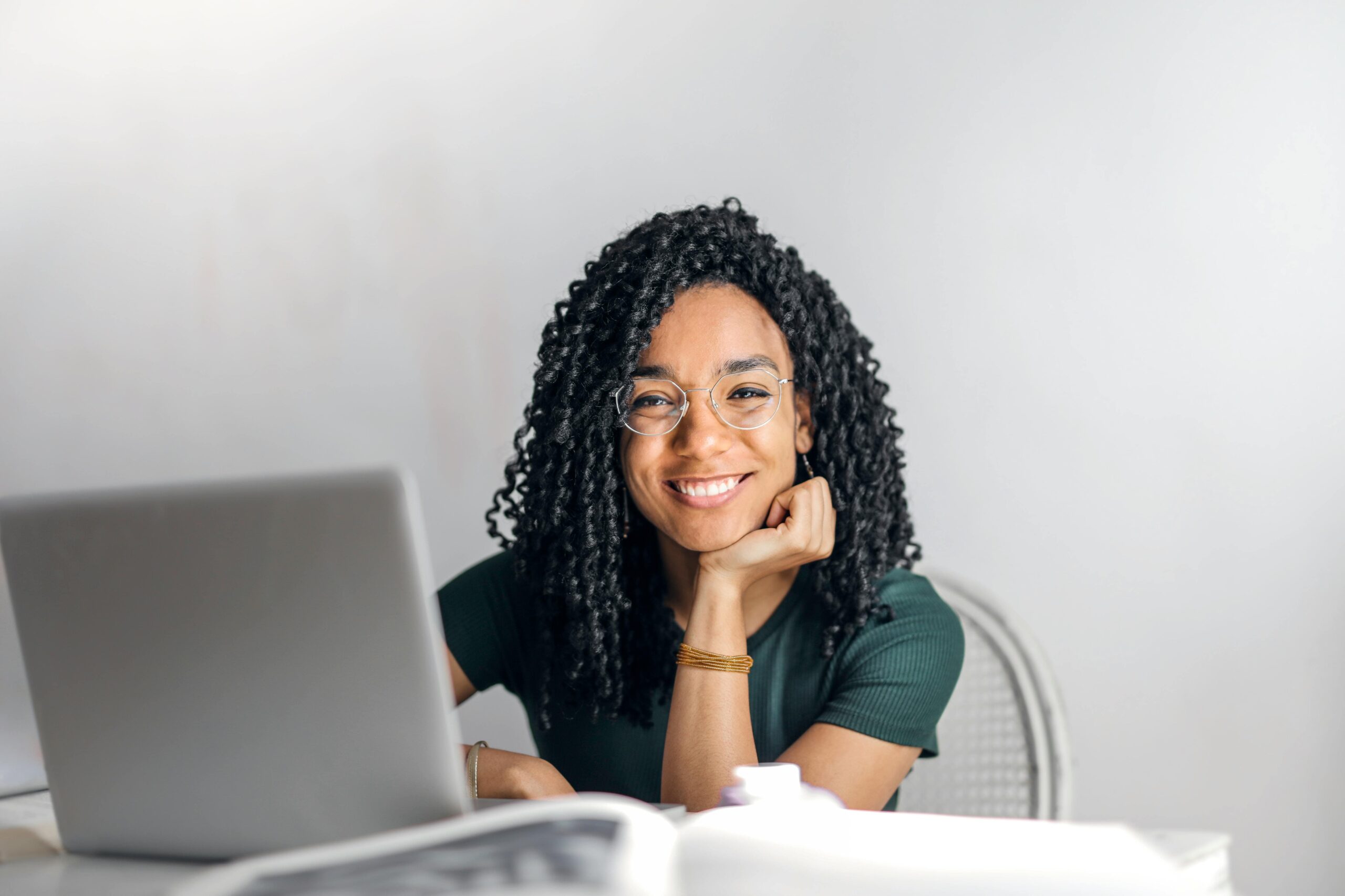 Women on computer, smiling at camera.